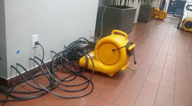 Yellow air mover and coiled cables on a tiled floor