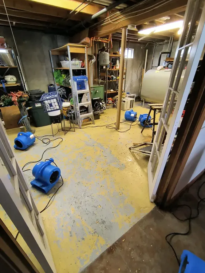 Air movers on a stripped floor beneath exposed framing
