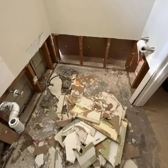 Removed wallboard and broken tile piled on a bathroom floor