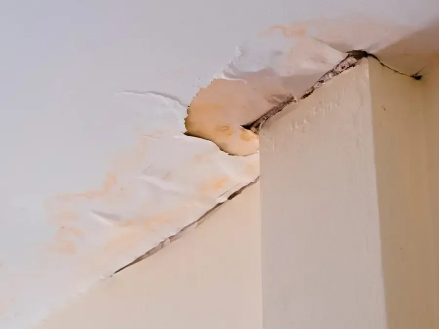 Brown water stains and cracked, peeling ceiling drywall at a wall corner